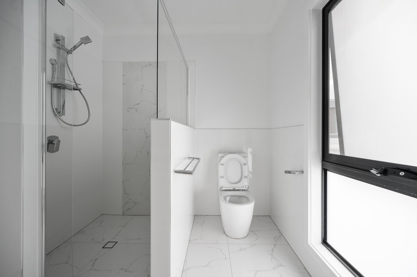 Bagno moderno con doccia a filo pavimento e vaso sospeso.