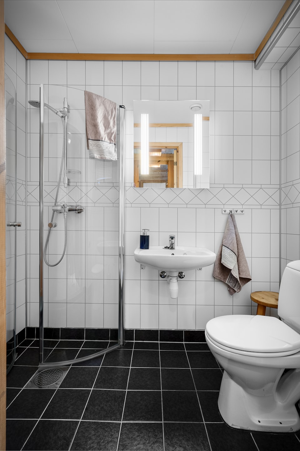 Bagno moderno con pareti piastrellate bianche e doccia in vetro.