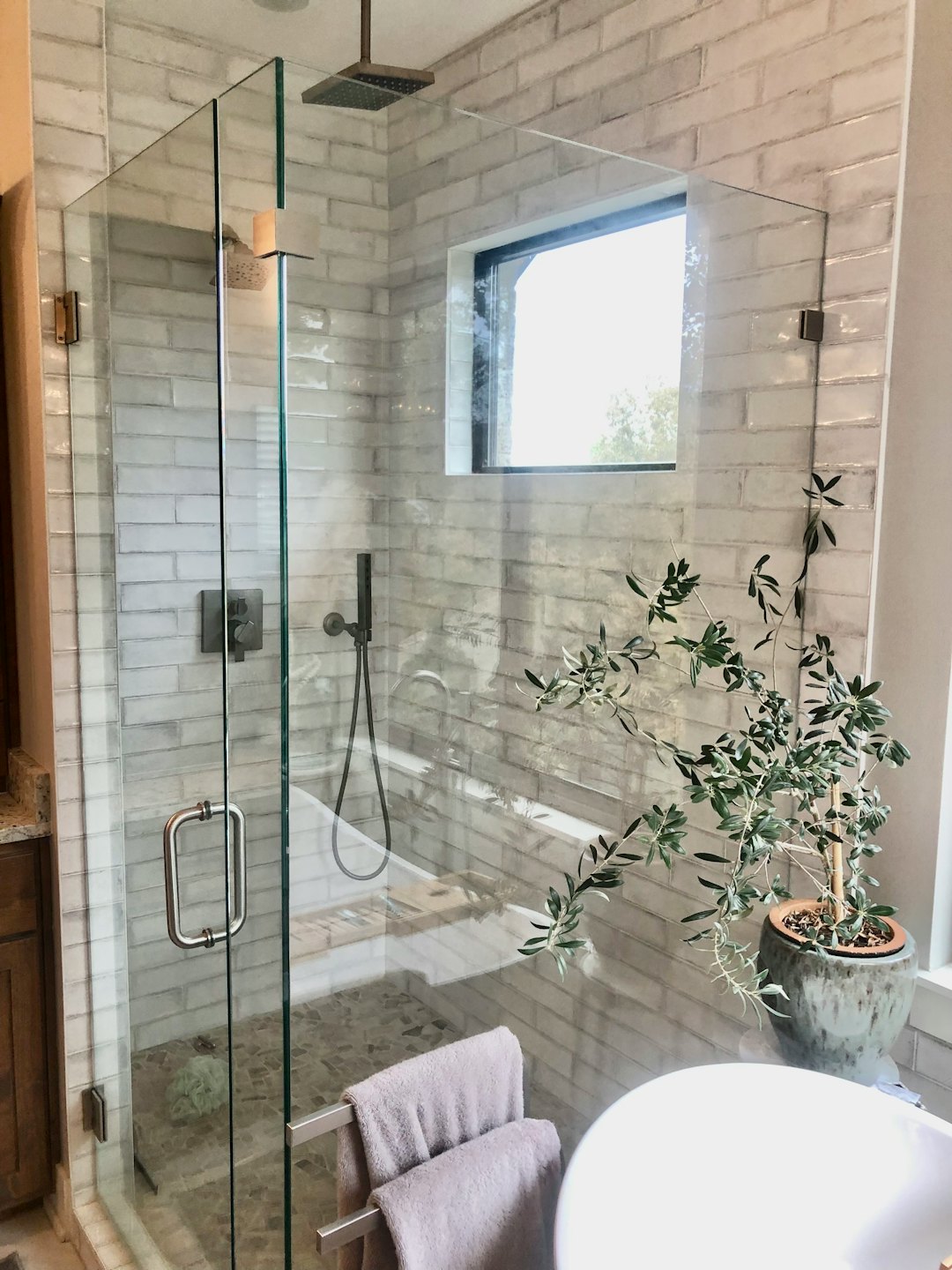 Bagno moderno con doccia in vetro e vasca bianca.
